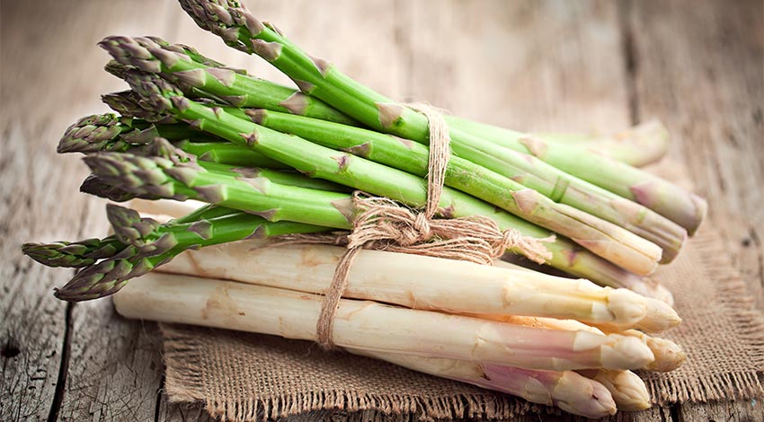 Grüner und weißer Spargel zusammengebunden präsentiert.